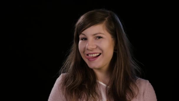 Une jeune femme souriante sur fond noir — Video