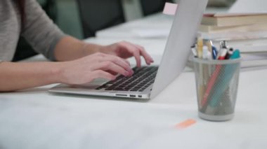 Office bir dizüstü bilgisayarda yazarak oturan bir Bayan