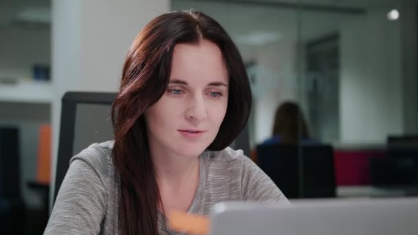 Дама сидить в офісі перед ноутбуком — стокове відео