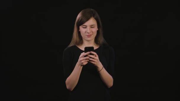 Een dame met behulp van een telefoon tegen een zwarte achtergrond — Stockvideo