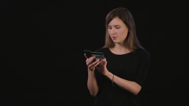 Uma senhora usando um telefone contra um fundo preto — Vídeo de Stock