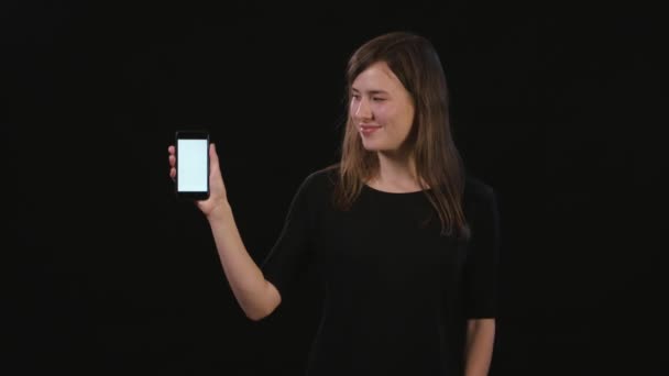 Een dame met behulp van een telefoon tegen een zwarte achtergrond — Stockvideo