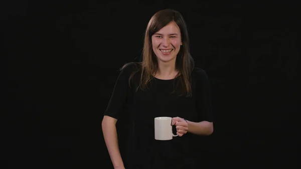 Eine Dame mit einer Tasse vor schwarzem Hintergrund — Stockfoto