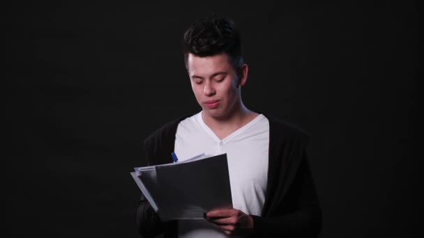 Ein junger Mann mimt vor schwarzem Hintergrund — Stockvideo