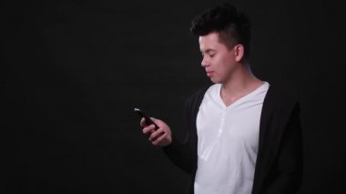 Siyah bir arka plan karşı bir telefonu kullanarak bir adam