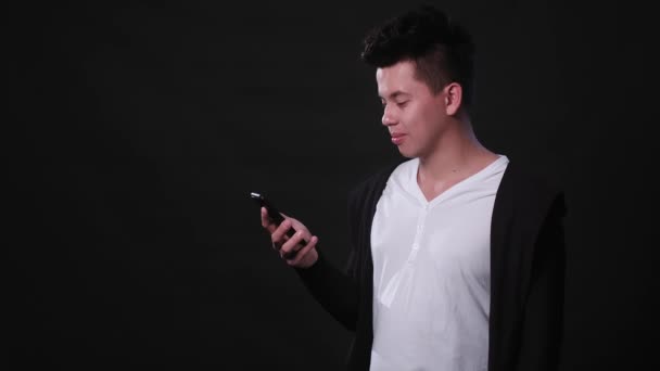 Un hombre usando un teléfono contra un fondo negro — Vídeo de stock