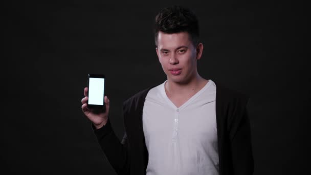 Un hombre sosteniendo un teléfono contra un fondo negro — Vídeo de stock