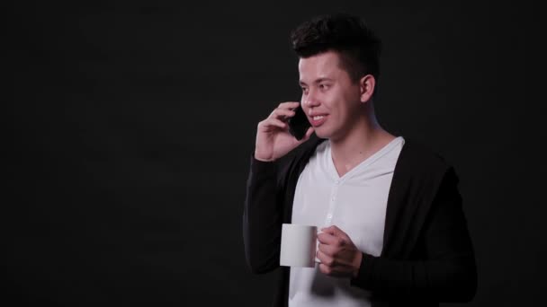 Un hombre usando un teléfono contra un fondo negro — Vídeos de Stock