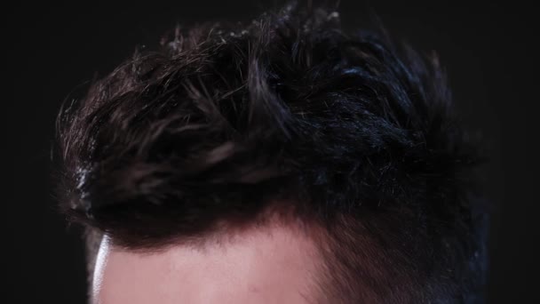 Man vidrör hans hår mot en svart bakgrund — Stockvideo