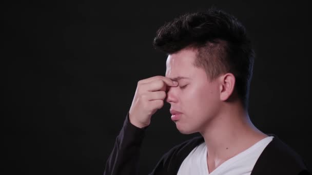 Een Man nabootsen hoofdpijn tegen een zwarte achtergrond — Stockvideo