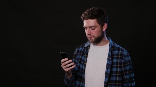 Ein Mann mit einem Telefon vor schwarzem Hintergrund — Stockvideo