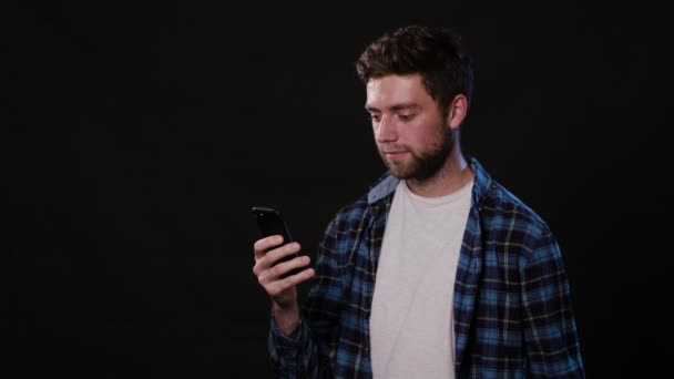 Un uomo che usa un telefono su uno sfondo nero — Video Stock