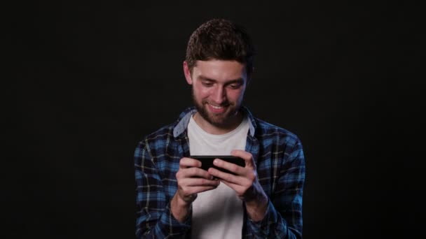 En Man som använder en telefon mot en svart bakgrund — Stockvideo