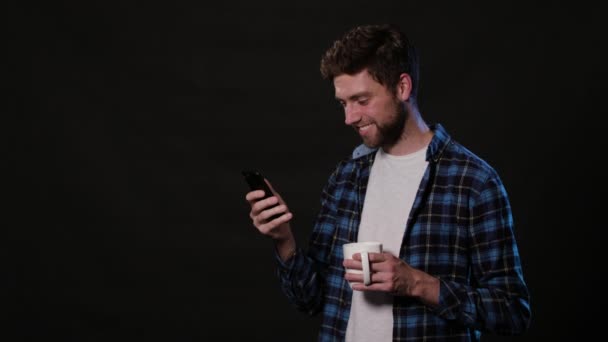 Um homem usando um telefone contra um fundo preto — Vídeo de Stock