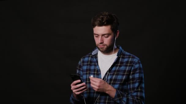 Um homem usando um telefone contra um fundo preto — Vídeo de Stock