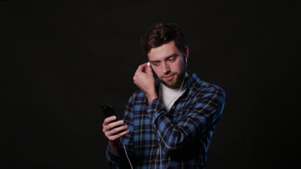 Un hombre usando un teléfono contra un fondo negro — Vídeo de stock