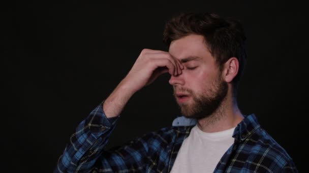 En Man imitera huvudvärk mot en svart bakgrund — Stockvideo