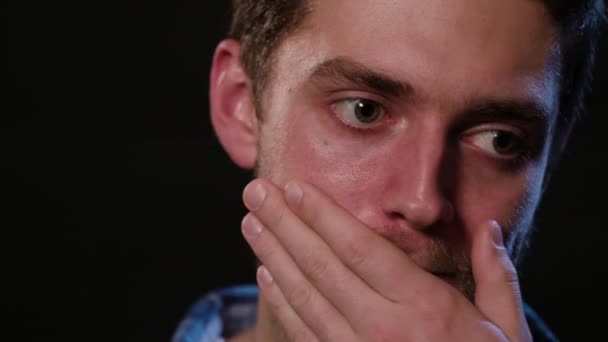 Um homem tocando seus lábios contra um fundo preto — Vídeo de Stock