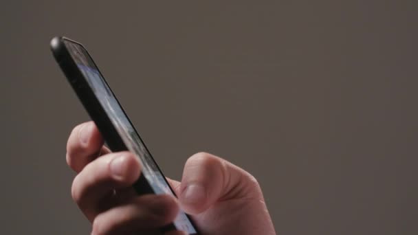 Una mano usando un teléfono inteligente contra un fondo oscuro — Vídeo de stock