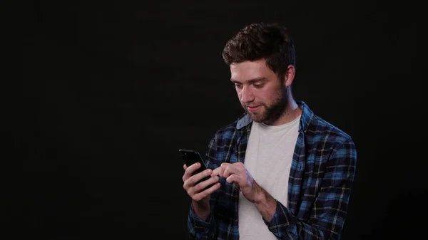 Um homem usando um telefone contra um fundo preto — Fotografia de Stock