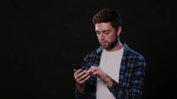 En Man som använder en telefon mot en svart bakgrund — Stockfoto