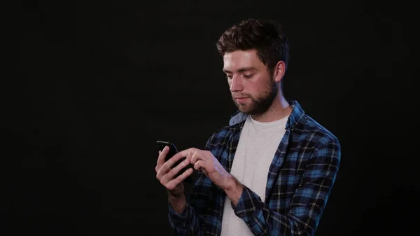 Un homme utilisant un téléphone sur fond noir — Photo