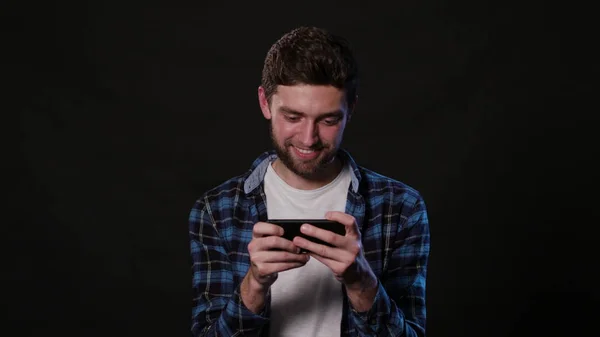 En Man som använder en telefon mot en svart bakgrund — Stockfoto