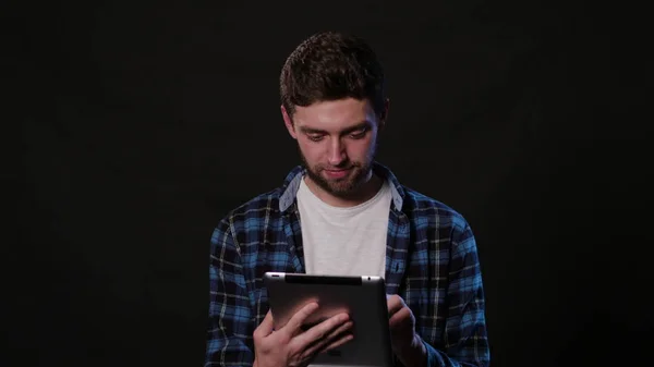 Een Man met een telefoon tegen een zwarte achtergrond — Stockfoto