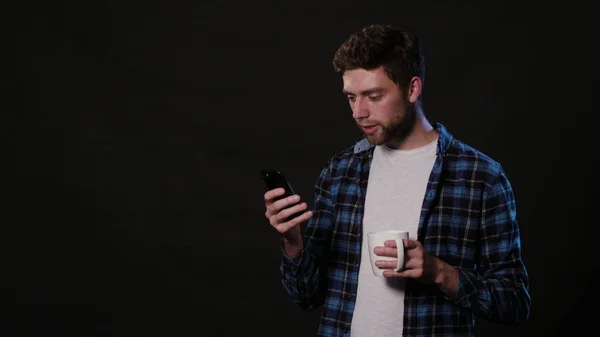 En Man som använder en telefon mot en svart bakgrund — Stockfoto