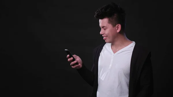 Un hombre usando un teléfono contra un fondo negro — Foto de Stock