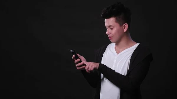 Siyah bir arka plan karşı bir telefonu kullanarak bir adam