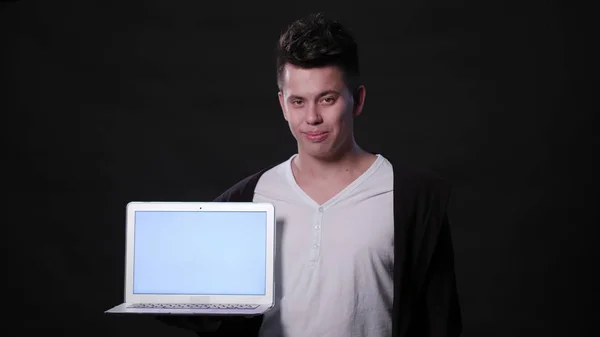 Um homem segurando um laptop contra um fundo preto — Fotografia de Stock