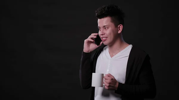 Un hombre usando un teléfono contra un fondo negro Imagen de archivo