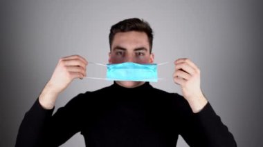 Adam koruyucu maske takıyor. Koruyucu ölçüler. Coronavirus covid-19 sosyal mesafesi. Beyaz adam koruyucu maske takarken önüne bakıyor.