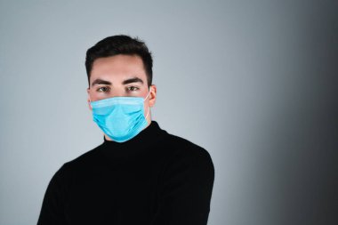 Adam koruyucu maske takıyor. Koruyucu ölçüler. Coronavirus covid-19 sosyal mesafesi. Beyaz adam koruyucu maske takarken önüne bakıyor.