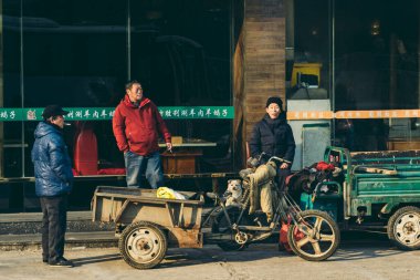 Beijing / China - 12/10/2018: Delivery Drivers waiting for parcels, packages, at the street on cold sunny morning clipart