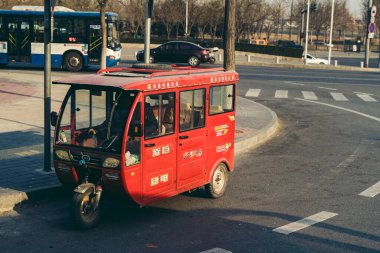 Pekin / Çin - 12 / 10 / 2018: Güneşli bir soğuk sabahta başkentin boş sokaklarında yolcu bekleyen kırmızı üç tekerlekli taksiler