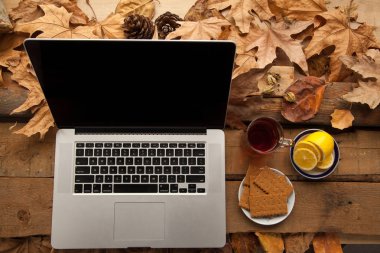 Sıcak çay ve limon ile ahşap masa üstünde laptop