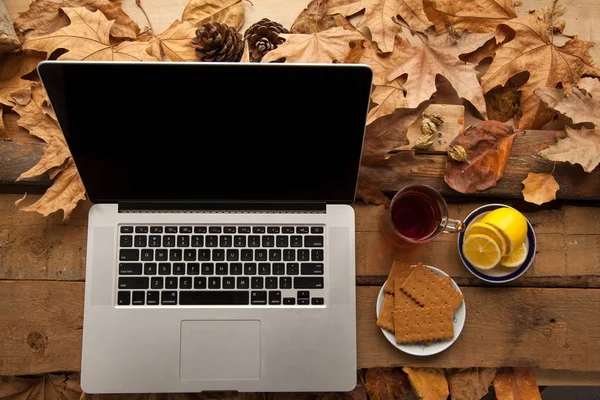 Sıcak çay ve limon ile ahşap masa üstünde laptop