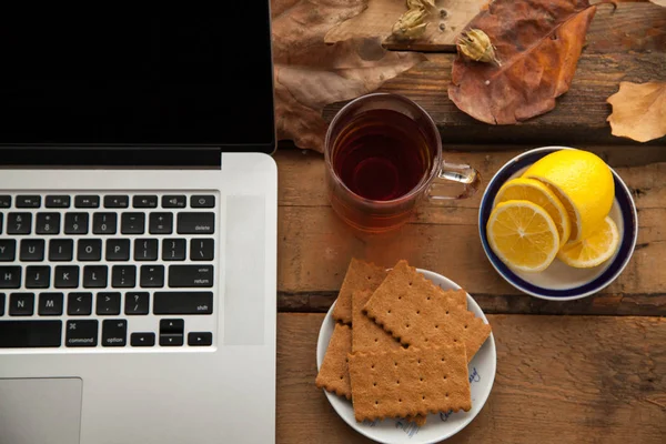 Sıcak çay ve limon ile ahşap masa üstünde laptop