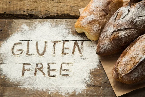 Bread on wooden table with scattered flour. — Stock Photo, Image