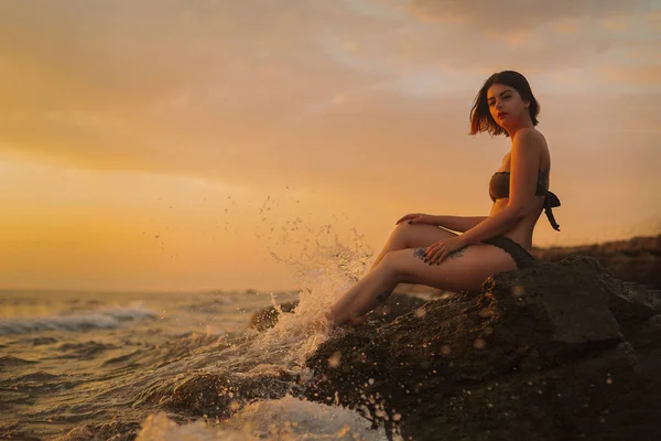 Bikini bir deniz bir kayaya oturan genç kız