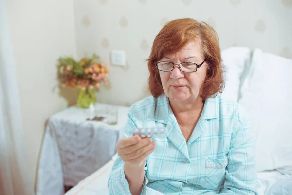 Senior woman in glasses, reading pills.