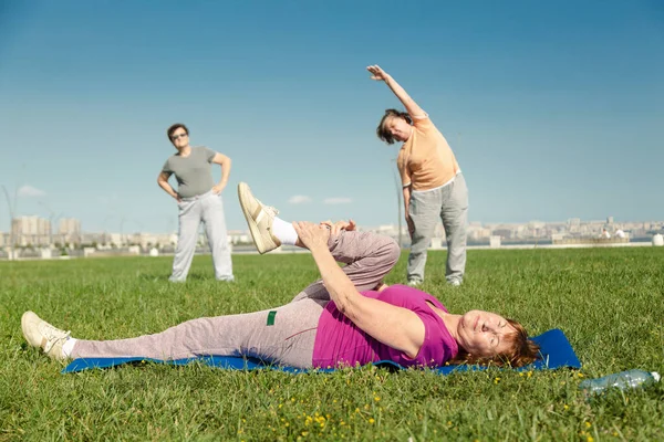 Starsze kobiety trenujące sport na zielonej trawie w parku publicznym. — Zdjęcie stockowe