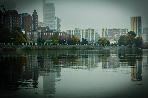 Το ποτάμι στην ομίχλη με την αντανάκλαση της πόλης και το ανάχωμα στην επιφάνεια του ποταμού — Φωτογραφία Αρχείου