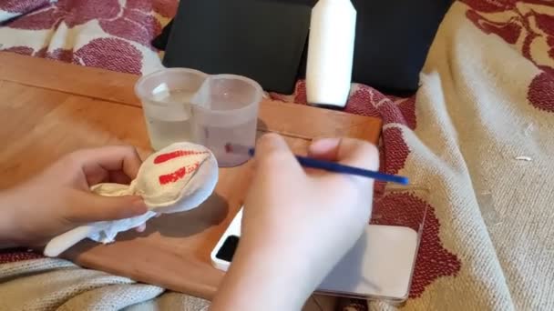 手はブラシでイースターエッグをペイント 女の子はイースターのために卵を描く イースターだ 手作りだ ホームビデオ 宿題だ 創造性の女の子 — ストック動画