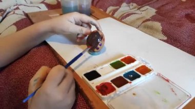 Kız Paskalya için suluboya yumurta boyuyor. Bu onun hobisi..