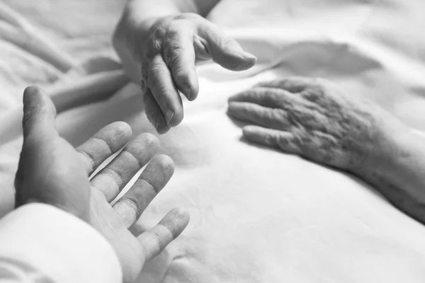 Tentando segurar uma mão de uma pessoa idosa — Fotografia de Stock