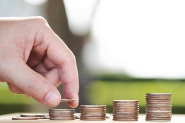 Para biriktiriyorum. İş adamı el, tasarruf, para, finans ve zenginliği arttırma kavramını göstermek için yığınla para koyuyor. Yumuşak odaklanma. İleti için açıklama yapmak için boşluk bırakın.