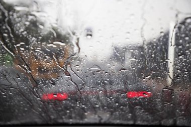 Akşam ları camın ön camına Yağmur Damlaları. şiddetli yağmurda sokak. Bokeh Kuyruk ışık ve trafik ışıkları şehirde. Lütfen arabayı dikkatli sür, kaygan yoldan. yumuşak odak.